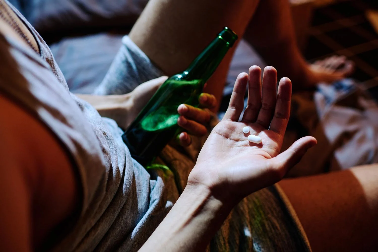 mano sosteniendo u n par de pastillas de drogas de diseño en una fiesta, piensa mezclarlos con cerveza
